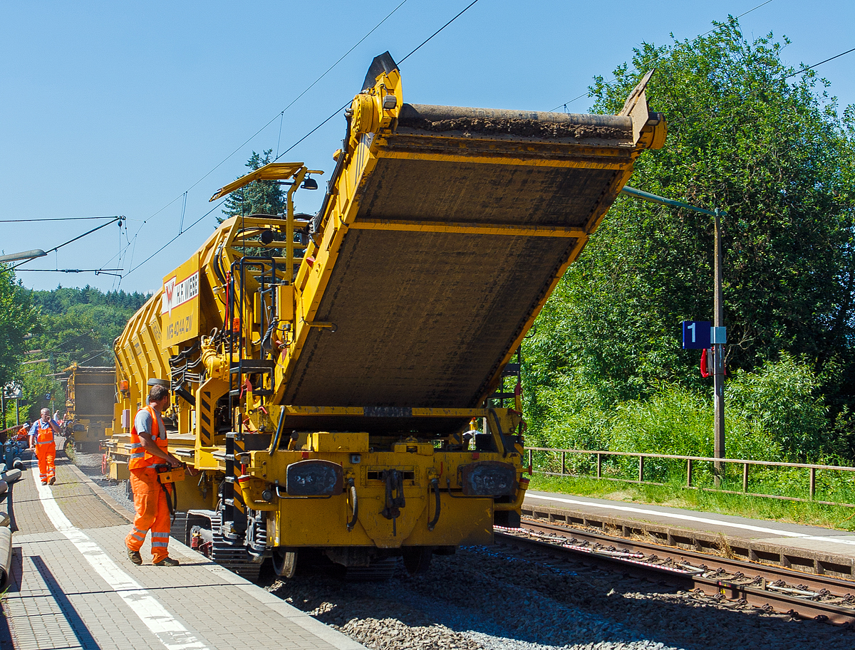 Baustelle im Bahnhof Katzenfurt (Lahn-Dill-Kreis) am 20.07.2013: Der MFS 40/4-A-ZW der H. F. Wiebe, Schweres Nebenfahrzeug 99 80 9052 002-9 D-GBM (ex 97 19 13 502 57-3) bringt den Aushub, auf dem z.Z. gleislosen 2. Gleisbett (fhrt auf Raupenfahrwerke), zu einer auf dem noch vorhandenen Gleis stehenden, gleisgebundenen Materialfrder- und Siloeinheit MFS 250 (H.F. Wiebe Bezeichnung Bunker-Schttgut-Wagen BSW 11000).