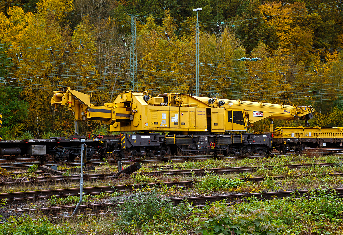 Der 150 t Kirow Gleisbaukran KRC 1200+ (ein Kirow MULTI TASKER KRC 1200+,  99 80 9419 005-0 D-BRS  „DONAU“  (ex 97 82 55 508 17-5) der STRABAG Rail GmbH ist am 27.10.2021 in Transportstellung in Betzdorf/Sieg abgestellt.  BRS steht für Strabag BMTI Rail Service GmbH (Berlin). 

Der Kran wurde 2009 von Kirow Ardelt AG in Leipzig unter der Fabriknummer 152500 gebaut. Er wird als Schweres Nebenfahrzeug Nr.: 99 80 9419 005-0 (ehemals 97 82 55 508 17-5) geführt und hat die EBA-Nr. EBA 09C02A001. 

Der Ausleger stützt sich auf dem Ausleger-Schutzwagen 99 80 9320 005-8 D-BRS ab und der Gegengewicht-Teleskoparm stützt sich auf dem Gegenlastwagen 99 80 9320 001-7 D-BRS ab.

Der Kran gehört zu einer der größten Gleisbaukranklassen, hat aber in der Transportstellung durch die Abstützungen auf den Kranauslegerschutzwagen und den Gegenlastwagen geringere Streckenlast (Meterlast) von max. 7,4 t/m, als seine kleineren Brüder.
Das Gegengewicht ist ausfahrbar und separat bis ± 30º  schwenkbar, sodass ein Einschwenken in den Bereich des Nachbargleises vermieden und ein profilfreies Arbeiten ermöglicht wird.

TECHNISCHE DATEN von dem Kran:
Spurweite: 1.435 mm
Eigengewicht  (in Transportstellung) : 111,0 t 
Länge über Puffer:  15.000 mm  (+13.000 mm Gegenlastwagen,+ 20.000 mm Ausleger-Schutzwagen)
Motorleistung:  254 kW bei 2.200 U/min
max. Geschwindigkeit im Zugverband: 100 km/h
max. Geschwindigkeit im Eigenantrieb: 19 km/h
Achsanzahl:  8 (in 4 Drehgestelle bzw. 2 Doppeldrehgestelle)
Drehzapfenabstand: 10.000 mm
Drehzapfenabstand im Drehgestell 1 und 2: 2.300 mm
Achsabstand in den Einzeldrehgestellen: 1.100mm
Ergebene Achsabstände in m: 1,1 / 1,2 / 1,1/ 6,6 / 1,1 / 1,2 / 1,1
Achsfolge: 1'A'1A'A1'A1'
Radsatzlast Transport Kran: max. 13,8 t
Radsatzlast Gegengewichtswagen:  max. 20,0 t
Meterlast (Streckenlast) in Transportstellung Kran max.: 7,4 t/m
Höhe in Transportstellung:  4.300 mm
Breite in Transportstellung:  3.100 mm
max. Ausladung vor Puffer:  21.000 mm
max. Traglast bei max. Ausladung:  40 t
Größte mögliche Traglast: 150 t (abgestützt)  / 120t (freistehend)
max. Hakenhöhe:  24.000 mm
hintere Ausladung (Gegenwicht):  7,9 m–13,5 m
Zul. Anhängelast: 160 t
Kleinster befahrbarer Radius: 80 m (120 m im Schleppbetrieb)

Besondere Ausstattung:
Überhöhenausgleich 180 mm
Schwenkradius ± 360º
Abstützung teleskopierbar bis 8 m Abstützbasis
profilfreies Arbeiten bis ± 30º