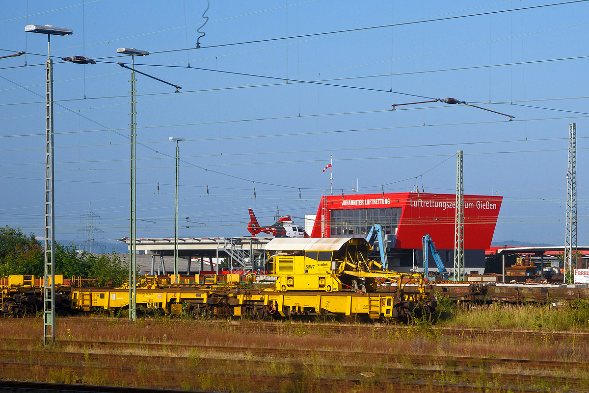 Der Schienenladewagen SLW 7, Schweres Nebenfahrzeug Nr. 97 30 08 907 57-6, der Vossloh Mobile Rail Services GmbH abgestellt mit Lanschienentransport am 05.09.2021 beim Bahnhof Gieen. Aufgenommen aus einem Zug heraus.

Der Schienenladewagen wurde 2007 von Maschinen- und Anlagenservice MAS GmbH in Guben unter der Fabriknummer 01/07 gebaut, wobei der Schienenmanipulator von Robel stammt und berarbeitet wurde. Das Eigengewicht betrgt 47 t, die Hchstgeschwindigkeit 120 km/h und der kleinste befahrbare Gleisbogen 80 mm.

Der Schienenladewagen dient zum Be- und Entladen von bis 180 m langen Schienen, auf/von den Schwellenkpfen bzw. in/aus Gleismitte. Der Einsatz erfolgt in Kombination mit Langschienentransporteinheiten der Bauart Robel. Die Be- bzw. Entladeleistung betrgt ca. 900 bis 1.400 m Gleis/Stunde.