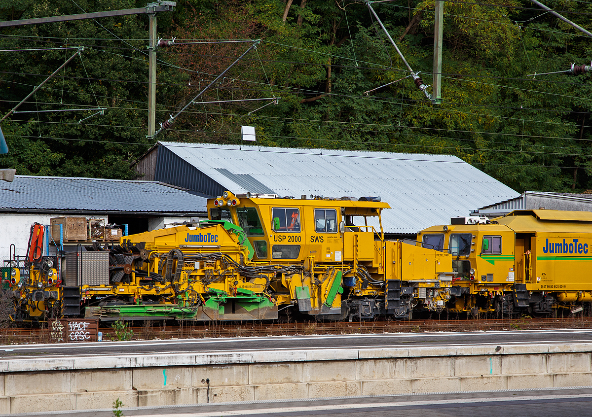 Die Plasser & Theurer  Universalschotterplaniermaschine USP 2000 SWS (Schweres Nebenfahrzeug Nr. 99 80 9424 036-8 D-JT, ex 97 16 32 502 17-7) der JumboTec GmbH (ein Unternehmen der Rhomberg Sersa Rail Group) ist am 17.10.2021 beim Bahnhof Au (Sieg) abgestellt.

Die Maschine wurde 2004 von Plasser & Theurer unter der Fabriknummer 766 gebaut.

TECHNISCHE DATEN:
Spurweite: 1.435 mm (Normalspur)
Anzahl der Achsen: 4
Lnge ber Puffer:  19.000 mm
Drehzapfenabstnde: 11.500 mm 
Achsabstand im Drehgestell: 1.800 mm / 1.500 mm
Raddurchmesser (neu): 730 mm
Eigengewicht:  51.920 kg
Nutzlast: - t
Zul. Anhngelast: 40 t
Leistung: ca. 400 kW 
Zur Mitfahrt zugel. Personenzahl: 3
Kleister befahrbarer Gleisbogen: R = 120 m
Zugelassen fr Streckenklasse: B1 und hher
Hchstgeschwindigkeit: 20 km/h (Eigenfahrt) 100 km/h (geschleppt)
Bremse: KE-GP mZ
Bremsgewichte: G 37 t / P 38 t