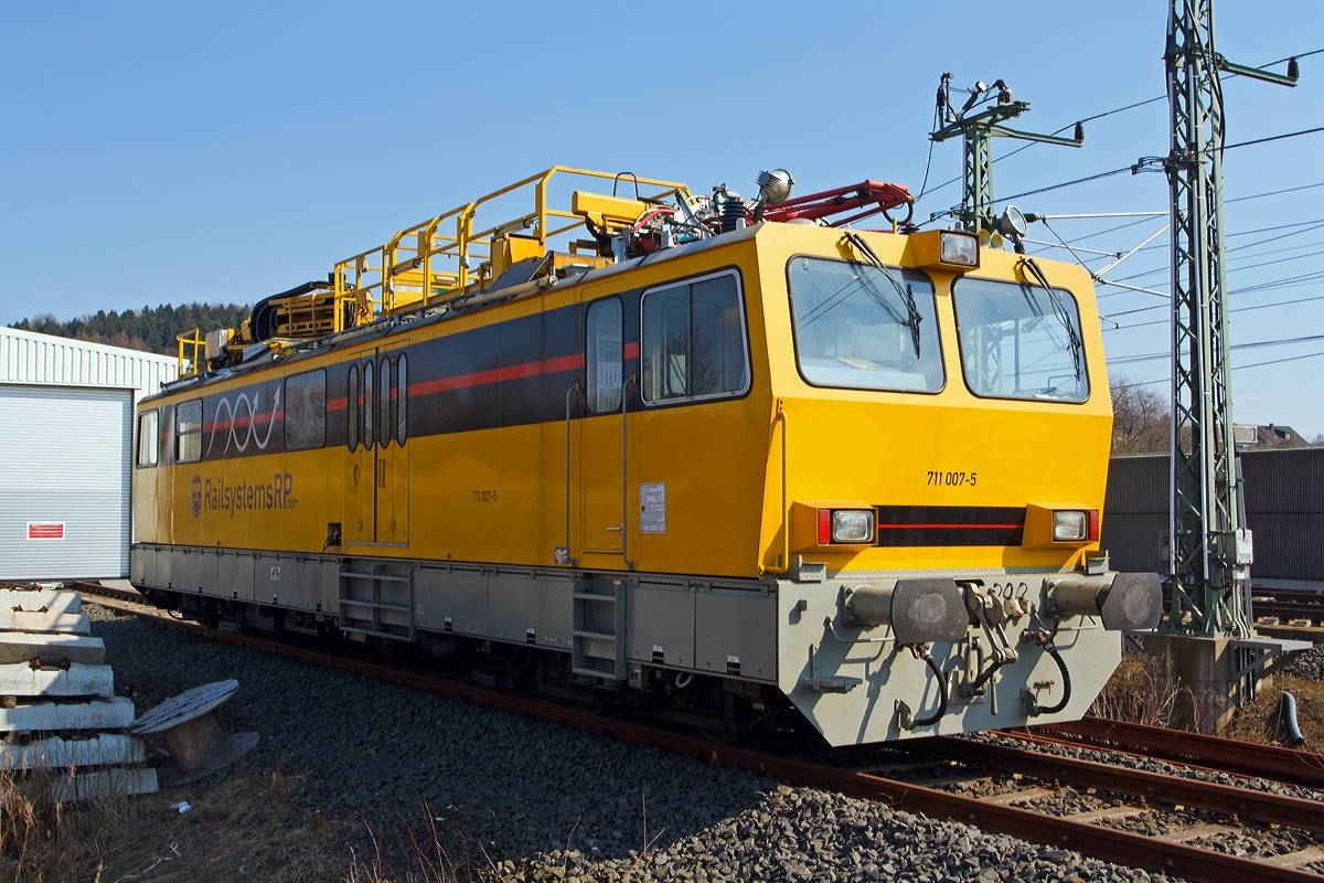 Hubarbeitsbühnen-Instandhaltungsfahrzeug für Oberleitungsanlagen (HIOB) 711 007-5 der RAILSYSTEMS RP GmbH (ex DB Netz AG 711 007-5), abgestellt am 07.04.2014 beim ICE-Bahnhof Montabaur.

Bei der Baureihe 711.0 handelt es sich um neun, in den Jahren 1995 und 1996 von Windhoff in Rheine gebaute Fahrzeuge zur Entstörung und Instandhaltung von Oberleitungsanlagen. Als Nachfolger für die älteren Turmtriebwagen bestellte die DB Netz bei der Firma Windhoff neun solcher Fahrzeuge.

Die Triebwagen der Baureihe 711.0 besitzen einen über die gesamte Rahmenlänge reichenden Wagenkasten in Stahlleichtbauweise. Der Wagenkasten beinhaltet einen 8.060 mm langen Werkstattraum, den Führerstand 1 mit 2.400 mm Länge und den kombinierten Aufenthaltsraum mit Führerstand 2, hier befinden sich auch der Videoarbeitsplatz und das Vakuum WC.

Auf dem Dach der Kabine befinden sich, angefangen über dem Führerstand 1, ein Messstromabnehmer der Bauart WBL 85 dessen Anpressdruck manuell regelbar ist, es folgt die Fahrdraht- und Tragseilhebeeinrichtung von dem Hersteller Atlas, anschließend ist eine Hubarbeitsbühne mit den Abmessungen 3.500 mm x 1.600 mm vorhanden, diese kann hydraulisch um 1.400 mm angehoben werden. Mit der Hubarbeitsbühne kombinierbar ist die freischwenkbare Hubarbeitsbühne, mit den Abmessungen 1.500 mm x 1.600 mm. Beide Bühnen erreichen im Gleichlauf eine maximale Höhe über SO von 5.200 mm, die freischwenkbare Hubarbeitsbühne alleine bis zu 20 m. Zuletzt ist noch eine Videokamera vorhanden, welche ein Bild des angelegten Stromabnehmers an den Videoarbeitsplatz sendet, von wo aus die Aufzeichnungen in Echtzeit kommentiert werden können.

Die  HIOB  verfügen über ein Lauf- und ein Triebdrehgestell, beide sind annähernd baugleich und besitzen zwei durch Megifedern geführte Achsen mit Monoblockrädern. Verzögert werden die Fahrzeuge durch eine Motor- und eine Druckluftbremse. Die selbsttätige indirekte und die nichtselbsttätige direkte Druckluftbremse wirken jeweils auf Graugussbremsklötze an allen Achsen, beide Bremsen sind mehrlösig. Zum Festhalten des stehenden Fahrzeugs ist eine elektropneumatisch gesteuerte Federspeicherbremse vorhanden.

Für die Streckenfahrt ist ein 6-Zylinder-MAN-Dieselmotor mit Abgasturbolader und Ladeluftkühlung vom Typ D 2876 LOH 01 vorhanden, dieser hat eine Leistung von 338 kW (460 PS) bei 1.800/min. Die Leistungsübertragung geschieht über ein hydrodynamisches Getriebe auf beide Achsen des Triebdrehgestells.
Für die Arbeitsfahrt bzw. für den Antrieb der Hydraulikpumpe wurde ein 4-Zylinder-MAN-Dieselmotor vom Typ D 0824 LFL 02 mit 118 kW (160 PS) bei 2.400/min verbaut. Der erzeugte Öldruck treibt unteranderem einen in den Antriebsstrang eingebauten Hydraulikmotor an. Durch diese Bauweise ist es möglich für Streckenfahrt, mit höherer Geschwindigkeit, beide Motoren parallel zu betreiben, um so eine recht hohe Leistung zu erhalten.

Für den Betrieb sind zwei Stromsysteme installiert. Zur Nutzung von handelsüblichen Werkzeugen ist ein Drehstromnetz 230/400 V mit 10 kVA vorhanden. Das gesamte Fahrzeug wird durch ein 24 V-Netz betrieben, das seine Energie aus Batterien und, von den Motoren angetriebene, Lichtmaschinen bezieht. Des Weiteren können die Batterien über einen 230 V-Fremdspannungsanschluss geladen werden.

Gesteuert wird das Fahrzeug über eine integrierte Fahrzeugsteuerung von Krauss-Maffei, diese übernimmt die Regelung, Überwachung und Diagnose aller relevanten Funktionen. Antriebs- und Bremsbefehle werden über einen, auf dem Führerpult integrierten, kombinierten Fahr-/Bremshebel erteilt. Für deutsche Triebfahrzeuge fast selbstverständlich sind herstellerseitig eine Indusi I 60R, eine Zeit/Zeit Sifa und Zugfunk. Außerdem haben die Fahrzeugen 711 007 bis 009 eine LZB 80 eingebaut.

Das Fahrzeug, wie auch 711 002 und 009, wurde 2009 von der DB Netz AG an die Railsystems RP GmbH verkauft.

Seine technischen Möglichkeiten:
- frei um ca.330° schwenkbare Hubarbeitsbühne mit eine Auslegung von 20 m Höhe und bis 12 m seitlich (z.B. 18 m auf 8 m seitlich)
- Scherenhub- und Montagebühne Länge 5,00 m, Arbeitshöhe Bühnenboden: 3,80 ࠓ 5,20m üSO
- Fahrdraht- und Tragseilanhebevorrichtung bis 8,0m üSO, seitliche Verschiebbarkeit 600 mm
- Meßstromabnehmer zur Messung der Fahrdrahtlage und Kettenwerke mit Videoaufzeichnung, nach Umbauarbeiten
- Abgasfilter für Tunnelarbeiten
- Arbeits- und Revisionsfahrt 0,5 - 10 km/h
Somit besitzt das Fahrzeug alle notwendigen Anlagen zur Oberleitungsmontage, Instandhaltung und Havariebeseitigung.

Technische Daten:
Hersteller: Windhoff Bahn- und Anlagentechnik GmbH, Rheine
Fabriknummer: 2433 (am Fahrzeug konnte ich jedoch 160 727/7 lesen)
Baujahr: 1996
EBA-Nummer: EBA 95S02M 007

Spurweite: 1.435 mm
Achsformel: 2'B'
Länge über Puffer: 17.240 mm
Höhe: 4.680 mm (Grundstellung der Geräte)
Breite: 3.000 mm
Drehzapfenabstand: 11.000 mm
Drehgestellachsstand: 1.800 mm
Leergewicht: 61,0 t
Dienstgewicht: 66,0 t
Radsatzfahrmasse: max. 16,5 t
Nutzlast: 5 t
Zul. Anhängelast: 80 t
Höchstgeschwindigkeit: 120 km/h
Zul. Schleppgeschwindigkeit: 140 km/h
Zur Mitfahrt zugel. Personen: 12
Zugelassene Streckenklasse: B2 oder höher
Traktionsleistung: 6-Zylinder-MAN-Dieselmotor mit Abgasturbolader und Ladeluftkühlung vom Typ D 2876 LOH 01 mit einer Leistung von 338 kW (460 PS)
Arbeitsmotor: 4-Zylinder-MAN-Dieselmotor vom Typ D 0824 LFL 02 mit 118 kW (160 PS) Leistung bei 2.400/min
Leistungsübertragung: hydrodynamisch (bzw. hydraulisch bei Arbeitsfahrt)
Bremse: KE-P m. Z
Lokbremse: Federspeicher 