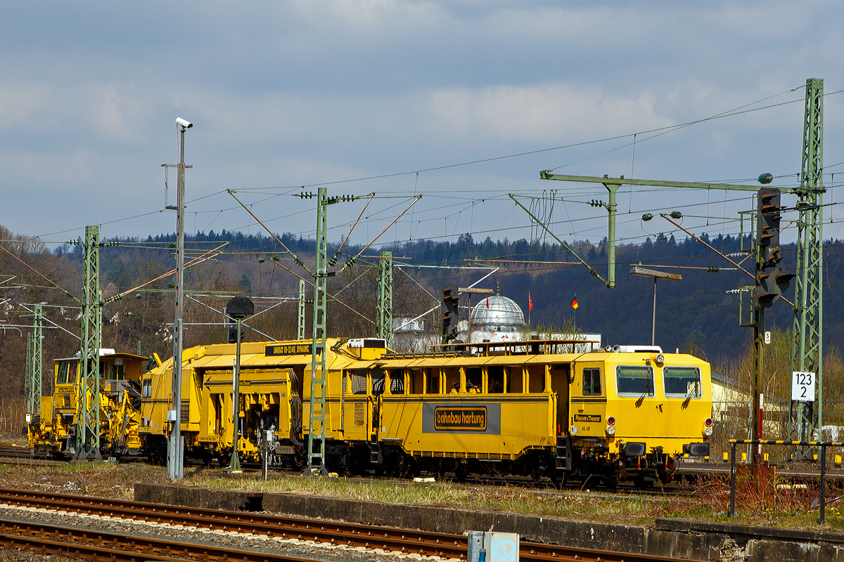 Leider etwas ungeschickt mit den Masten davor.... 
Die Plasser & Theurer Universalstopfmaschine UNIMAT 09-32/4S DYNAMIC,  Alles wird gut! , Schweres Nebenfahrzeug Nr. 99 80 9421 020-5 D-HBAU, ex 97 43 55 505 17-9, und die P&T Schnell-Schotterplaniermaschine SSP 110 SW,   Alles wird gut! , Schweres Nebenfahrzeug Nr. 99 80 9425 100-1, ex 97 16 46 507 18-8, beide von der Hartung-Bau GmbH (Fulda-Krämmerzell), fahren am 20.04.2021 im Verband durch Betzdorf/Sieg in Richtung Siegen.

Beide Maschinen wurden 2004 von Plasser & Theurer in Linz (A) gebaut, die Universalstopfmaschine unter der Fabriknummer 3138 und die Schotterplaniermaschine unter der Fabriknummer 750.