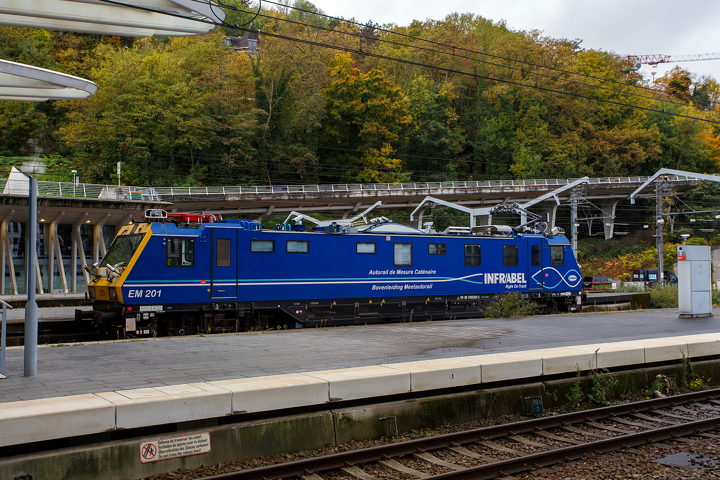 Der Oberleitungsmesstriebwagen (Autorail de Mesure Caténaire) EM 201 mit der UIC-Nummer 99 88 9165 201-3 B-INFBL, ein Geismar Eye Dragon VMB2214-IC der belgischen INFRABEL am 21 Oktober 2025 beim Bahnhof Lüttich-Guillemins (Gare de Liège-Guillemins). Kurzdrauf fuhr der Messtriebwagen die Schnellfahrstrecke in Richtung Ans bzw. Brüssel hinauf. 
Die Infrabel ist das 2005 aus der Privatisierung der Eisenbahn in Belgien hervorgegangene Infrastrukturunternehmen. Es ist vollständig im Eigentum des belgischen Staates und hat etwa 12.750 Mitarbeiter. Seine Aufgaben beinhalten die Instandhaltung sowie den Ausbau des 3602 km langen belgischen Schienennetzes, die Vergabe und Abrechnung von Fahrplantrassen sowie die Koordination des belgischen Zugverkehrs.
Die Infrabel hat 3 dieser Messtriebwagen vom Typ Geismar VMB2214-IC, die zwischen 2010 und 2014 gebaut wurden. Sie sind als Serie EM200 eingeordnet.
TECHNISCHE DATEN des Messtriebwagen:
Spurweite: 1.435 mm (Normalspur)
Achsfolge: Bo-Bo
Länge über Puffer: 21.240 mm
Drehzapfenabstand: 14.000 mm	
Achsabstand im Drehgestell: 2.500 mm
Gewicht: 89 t
min. Kurvenradius: R 90 m Der Oberleitungsmesstriebwagen (Autorail de Mesure Caténaire) EM 201 mit der UIC-Nummer 99 88 9165 201-3 B-INFBL, ein Geismar Eye Dragon VMB2214-IC der belgischen INFRABEL am 21 Oktober 2025 beim Bahnhof Lüttich-Guillemins (Gare de Liège-Guillemins). Kurzdrauf fuhr der Messtriebwagen die Schnellfahrstrecke in Richtung Ans bzw. Brüssel hinauf. 
Die Infrabel ist das 2005 aus der Privatisierung der Eisenbahn in Belgien hervorgegangene Infrastrukturunternehmen. Es ist vollständig im Eigentum des belgischen Staates und hat etwa 12.750 Mitarbeiter. Seine Aufgaben beinhalten die Instandhaltung sowie den Ausbau des 3602 km langen belgischen Schienennetzes, die Vergabe und Abrechnung von Fahrplantrassen sowie die Koordination des belgischen Zugverkehrs.
Die Infrabel hat 3 dieser Messtriebwagen vom Typ Geismar VMB2214-IC, die zwischen 2010 und 2014 gebaut wurden. Sie sind als Serie EM200 eingeordnet.
TECHNISCHE DATEN des Messtriebwagen:
Spurweite: 1.435 mm (Normalspur)
Achsfolge: Bo-Bo
Länge über Puffer: 21.240 mm
Drehzapfenabstand: 14.000 mm	
Achsabstand im Drehgestell: 2.500 mm
Gewicht: 89 t
min. Kurvenradius: R 90 m