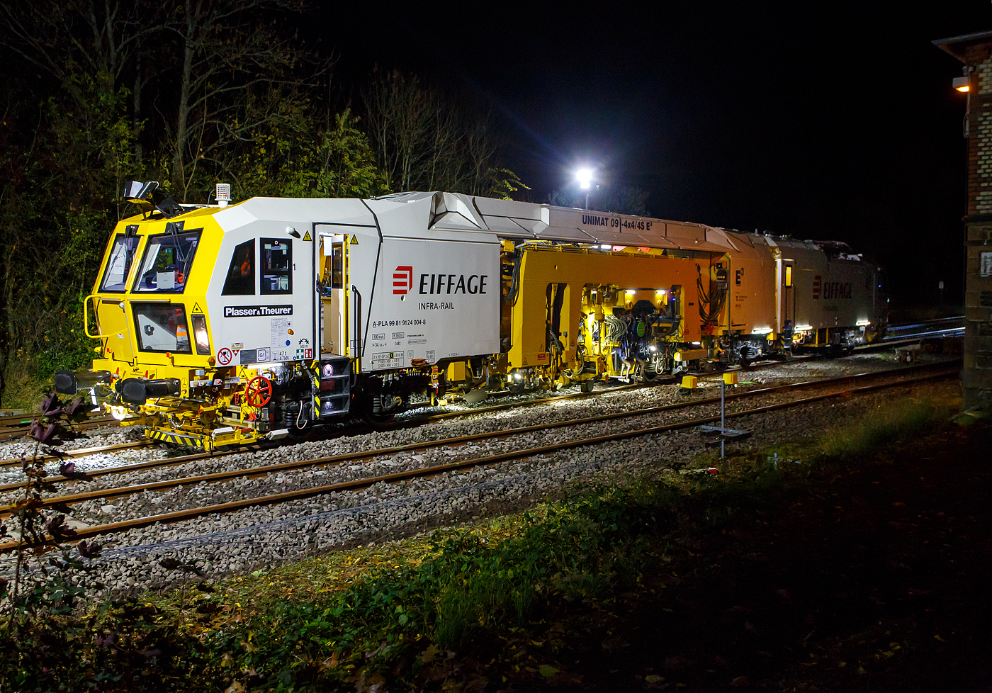 Die Baustelle Bahnhof Herdorf am Abend des 26 Oktober 2025, nun ab 20:40 Uhr wird die neue Weiche 3, beim Bahnhof/Stellwerk Herdorf Fahrdienstleiter (Hf), gestopft. Hier kam die recht neue Plasser & Theurer UNIMAT 09-4x4/4S E³ (A-PLA 99 81 9124 004-8), eine Universal-Weichenstopfmaschine mit Hybrid-Antriebstechnik, der Firma Eiffage Infra-Rail GmbH (Herne) zum Einsatz. Ob die Maschine nur von Eiffage Infra-Rail gemietet oder nun gekaut wurde ist mir nicht klar, aber eingestellt ist sie in Österreich über Franz Plasser Vermietung von Bahnbaumaschinen GmbH. 
Die Maschine wurde 2017 von Plasser & Theurer in Linz unter der Fabriknummer 6557/58 gebaut. Diese Maschine mit der neuen E³-Antriebstechnologie von Plasser & Theurer wurde erstmals 2017 auf der iaf 2017 in Münster präsentiert, wo ich sie am 01.06.2017 auch ablichten und sogar in ihr Platz nehmen konnte. Siehe u.a.:
http://hellertal.startbilder.de/bild/oesterreich~bahndienstfahrzeuge~stopfmaschinen/572409/neues-maschinendesign-und-neue-e179-antriebstechnologie-von.html
und
http://hellertal.startbilder.de/bild/oesterreich~bahndienstfahrzeuge~stopfmaschinen/572406/der-blick-des-maschinenfuehrers-auf-das.html
Leider ist die Helltalbahn nicht elektrifiziert, somit konnte die Maschine den Bahnhof Herdorf nur mit Dieselantrieb (diesel-elektrisch) anfahren und nur im Dieselbetrieb arbeiten. Wenn aber eine Oberleitung vorhanden ist, dann kann die Maschine auch rein elektrisch arbeiten. 
Die Fahrantriebe sind elektrisch im Dieselbetrieb diesel-elektrisch. Im Arbeitsmodus werden alle Drehbewegungen elektrisch, Linearbewegungen hydraulisch. Zudem wir im Dieselbetrieb überschüssige elektrische Energie ins Netz zurück gespeist. 
Der diesel-elektrisch angetriebener Fahrmodus und Arbeitsmodus:
Ein Dieselmotor mit einer Leistung von 600 kW liefert die Energie für die elektrische Versorgung der Antriebskomponenten über den Trafo und Stromrichter. Er wirkt dabei als Generator. Im Arbeitsbetrieb funktionieren die Aggregate gleichermaßen wie im elektrischen Modus. Wichtigster Vorteil ist die Reduktion von der CO2-Emission und von Lärm (10 dBA Lärmreduzierung). Weniger Triebstoffverbrauch, höhere Energieeffizienz im Diesel-elektrischen Betrieb. Ich konnte persönlich feststellen, dass die Maschine (auch beim Stopfen) erheblich leiser ist, als andere klassische Maschinen. 
TECHNISCHE DATEN:
Fahrzeugbegrenzungsprofil: G1
Spurweite: 1.435 mm (Normalspur)
Anzahl der Achsen: 8 (in 4 Drehgesten)
Länge über Puffer:  34.140 mm
Drehzapfenabstände: 11.250 mm / 4.550 mm / 10.300 mm
Achsabstand im Drehgestell: 1.800 mm
Raddurchmesser (neu): 920 mm
Eigengewicht: 142.000 kg
Kleister befahrbarer Gleisbogen: R = 150 m 
Zugelassen für Streckenklasse: C2 und höher
Höchstgeschwindigkeit: 100 km (eigen und geschleppt)
Kraftstofftank: max. 2.580 l (Diesel)
Wirkungsgrad: bis zu 94 %
Bremse:2 x KE-GP mZ (K)
Bremssohle: J 816 M Die Baustelle Bahnhof Herdorf am Abend des 26 Oktober 2025, nun ab 20:40 Uhr wird die neue Weiche 3, beim Bahnhof/Stellwerk Herdorf Fahrdienstleiter (Hf), gestopft. Hier kam die recht neue Plasser & Theurer UNIMAT 09-4x4/4S E³ (A-PLA 99 81 9124 004-8), eine Universal-Weichenstopfmaschine mit Hybrid-Antriebstechnik, der Firma Eiffage Infra-Rail GmbH (Herne) zum Einsatz. Ob die Maschine nur von Eiffage Infra-Rail gemietet oder nun gekaut wurde ist mir nicht klar, aber eingestellt ist sie in Österreich über Franz Plasser Vermietung von Bahnbaumaschinen GmbH. 
Die Maschine wurde 2017 von Plasser & Theurer in Linz unter der Fabriknummer 6557/58 gebaut. Diese Maschine mit der neuen E³-Antriebstechnologie von Plasser & Theurer wurde erstmals 2017 auf der iaf 2017 in Münster präsentiert, wo ich sie am 01.06.2017 auch ablichten und sogar in ihr Platz nehmen konnte. Siehe u.a.:
http://hellertal.startbilder.de/bild/oesterreich~bahndienstfahrzeuge~stopfmaschinen/572409/neues-maschinendesign-und-neue-e179-antriebstechnologie-von.html
und
http://hellertal.startbilder.de/bild/oesterreich~bahndienstfahrzeuge~stopfmaschinen/572406/der-blick-des-maschinenfuehrers-auf-das.html
Leider ist die Helltalbahn nicht elektrifiziert, somit konnte die Maschine den Bahnhof Herdorf nur mit Dieselantrieb (diesel-elektrisch) anfahren und nur im Dieselbetrieb arbeiten. Wenn aber eine Oberleitung vorhanden ist, dann kann die Maschine auch rein elektrisch arbeiten. 
Die Fahrantriebe sind elektrisch im Dieselbetrieb diesel-elektrisch. Im Arbeitsmodus werden alle Drehbewegungen elektrisch, Linearbewegungen hydraulisch. Zudem wir im Dieselbetrieb überschüssige elektrische Energie ins Netz zurück gespeist. 
Der diesel-elektrisch angetriebener Fahrmodus und Arbeitsmodus:
Ein Dieselmotor mit einer Leistung von 600 kW liefert die Energie für die elektrische Versorgung der Antriebskomponenten über den Trafo und Stromrichter. Er wirkt dabei als Generator. Im Arbeitsbetrieb funktionieren die Aggregate gleichermaßen wie im elektrischen Modus. Wichtigster Vorteil ist die Reduktion von der CO2-Emission und von Lärm (10 dBA Lärmreduzierung). Weniger Triebstoffverbrauch, höhere Energieeffizienz im Diesel-elektrischen Betrieb. Ich konnte persönlich feststellen, dass die Maschine (auch beim Stopfen) erheblich leiser ist, als andere klassische Maschinen. 
TECHNISCHE DATEN:
Fahrzeugbegrenzungsprofil: G1
Spurweite: 1.435 mm (Normalspur)
Anzahl der Achsen: 8 (in 4 Drehgesten)
Länge über Puffer:  34.140 mm
Drehzapfenabstände: 11.250 mm / 4.550 mm / 10.300 mm
Achsabstand im Drehgestell: 1.800 mm
Raddurchmesser (neu): 920 mm
Eigengewicht: 142.000 kg
Kleister befahrbarer Gleisbogen: R = 150 m 
Zugelassen für Streckenklasse: C2 und höher
Höchstgeschwindigkeit: 100 km (eigen und geschleppt)
Kraftstofftank: max. 2.580 l (Diesel)
Wirkungsgrad: bis zu 94 %
Bremse:2 x KE-GP mZ (K)
Bremssohle: J 816 M